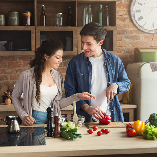 Photo of young couple in kitchen prepping healthy meal.